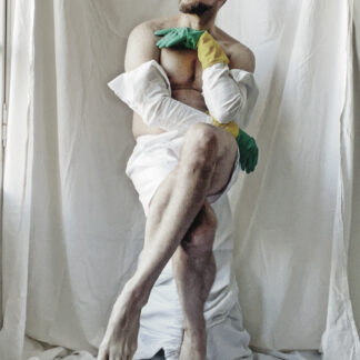 In this photographic series, I approach femininity not as an identity to possess, but as a gesture to rehearse. The body presented is unmistakably male — middle-aged, imperfect, vulnerable — yet it inhabits poses historically coded as feminine: crossed legs, softened wrists, exposed torso, contained posture. These gestures are not parody. They are practice. I am interested in the tension between masculinity as inheritance and femininity as possibility. In Western visual history, the male body has often been depicted as heroic, assertive, monumental. Here, the body withdraws. It folds into itself. It hesitates. It listens. The domestic rubber gloves — green and yellow — introduce another layer of coded femininity: care, maintenance, cleaning, the invisible labor traditionally assigned to women. Worn over a partially removed white garment, they blur the boundary between protection and costume, between intimacy and performance. The white draped fabric surrounding the figure references classical sculpture and religious iconography, but it also evokes a provisional stage — a space where identity can be rehearsed without resolution. “Practicing Femininity” does not claim transformation. It proposes vulnerability as a method. Within the framework of fluid femininity, I understand gender not as a fixed state but as a choreography of learned gestures — repeated, resisted, and sometimes reclaimed. This work asks: What happens when a male body allows itself to inhabit softness without irony? When femininity is not appropriated, but practiced as a form of unlearning? The images are not declarations. They are rehearsals.