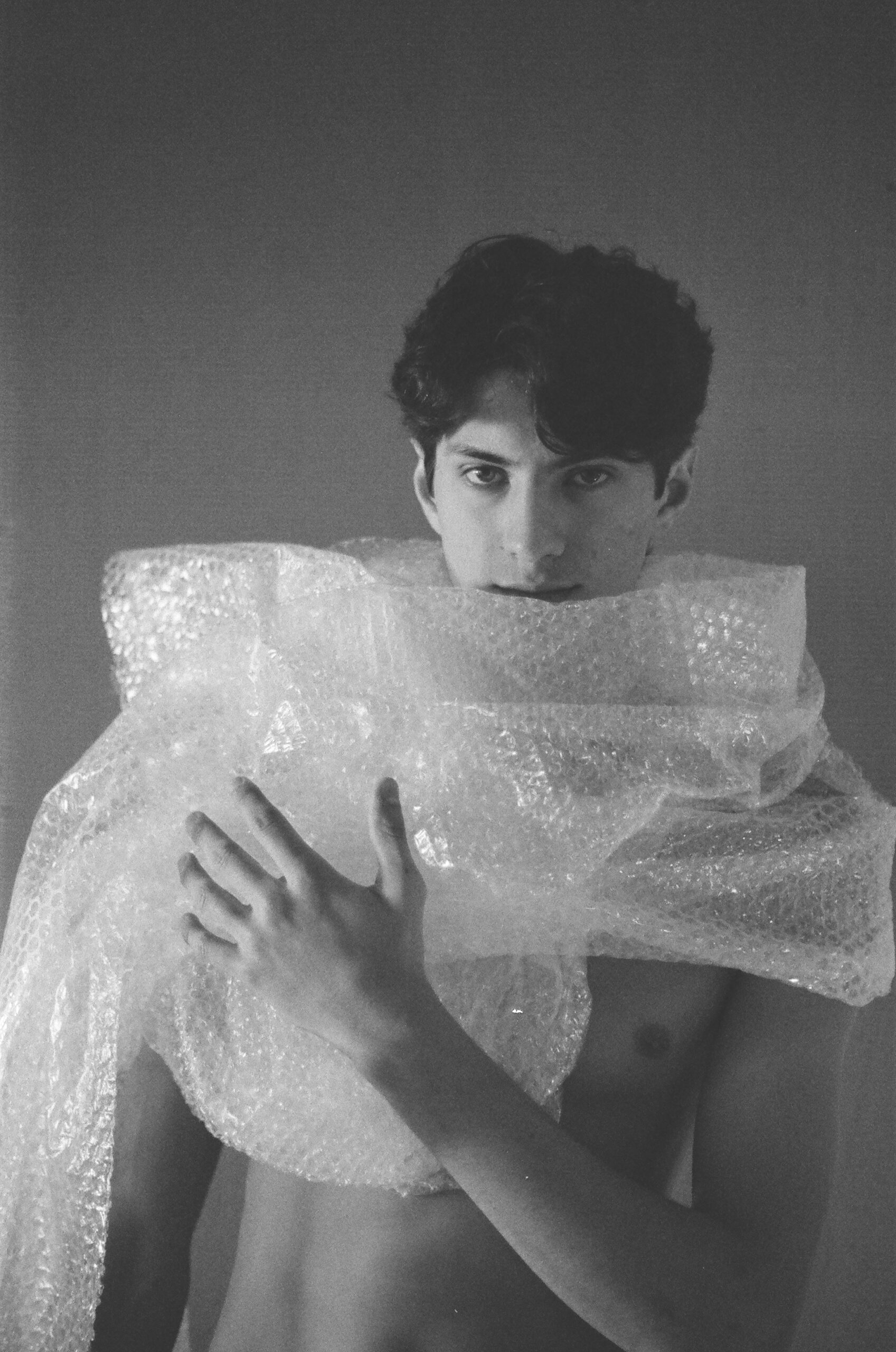 Analog photograph of a bare male torso partially covered with bubble wrap, exploring masculinity, protection, fragility and artificiality.